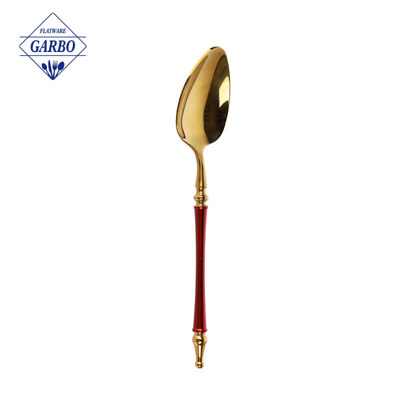 印象的なレッドペイントのハンドルが付いたステンレススチール製のゴールドディナースプーンをご覧ください。