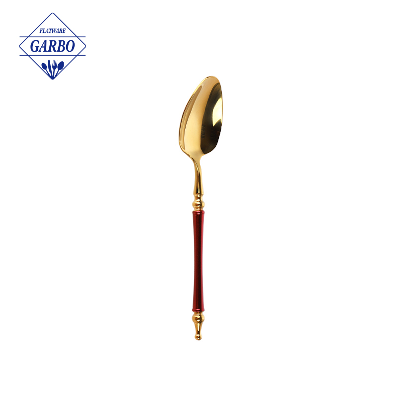 印象的なレッドペイントのハンドルが付いたステンレススチール製のゴールドディナースプーンをご覧ください。